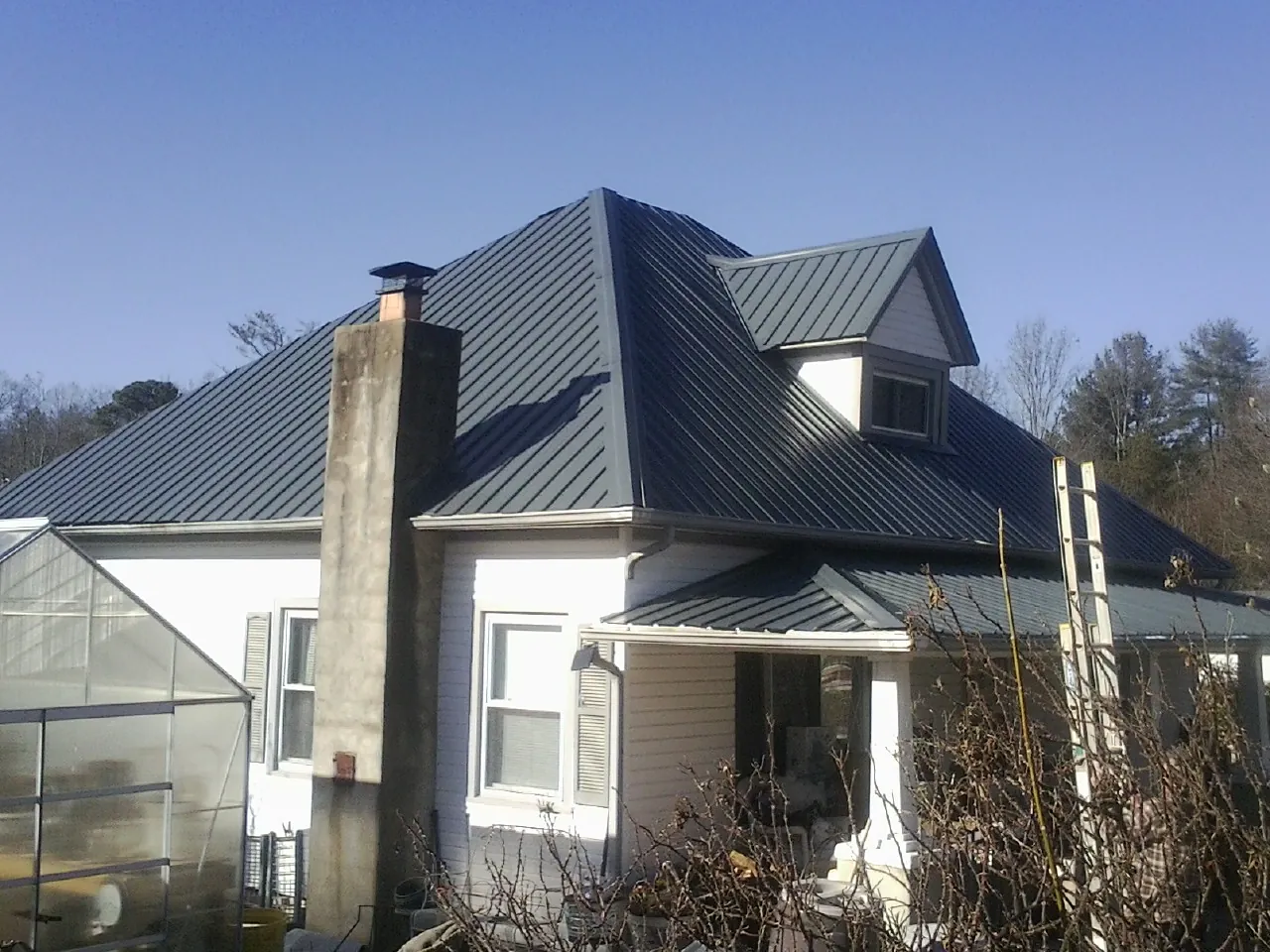 Dark blue standing seam metal roof on a white farmhouse with dormer — Slate & Tile Roof Repair by Roofing Brothers in Chattaroy