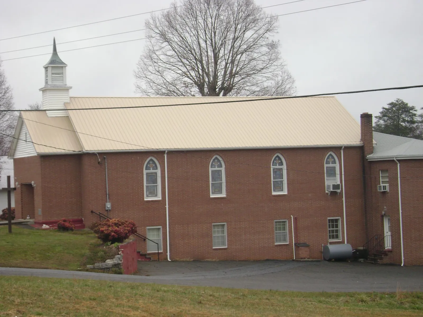 New tan metal roof on a brick church with a white steeple in Chattaroy