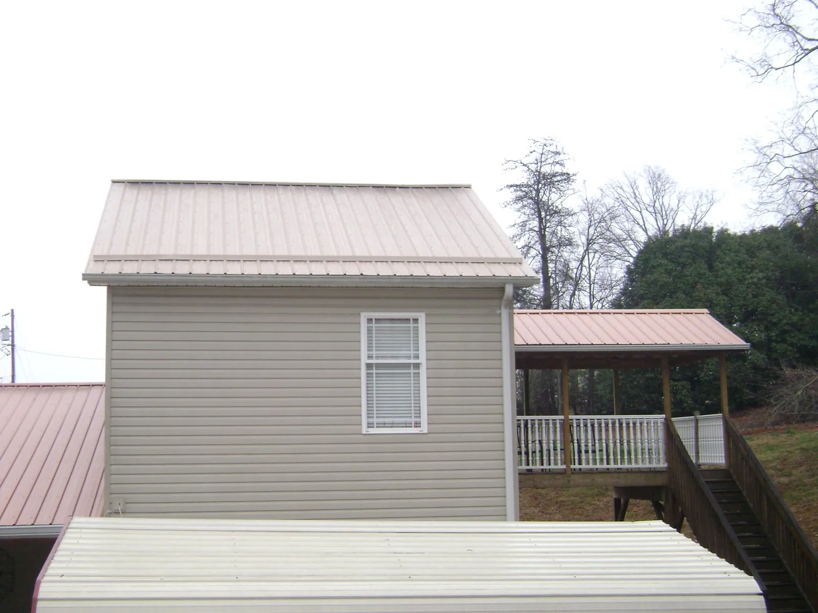 Tan metal roofs on a two story addition and attached porch, from a Roof Replacement job in Chattaroy