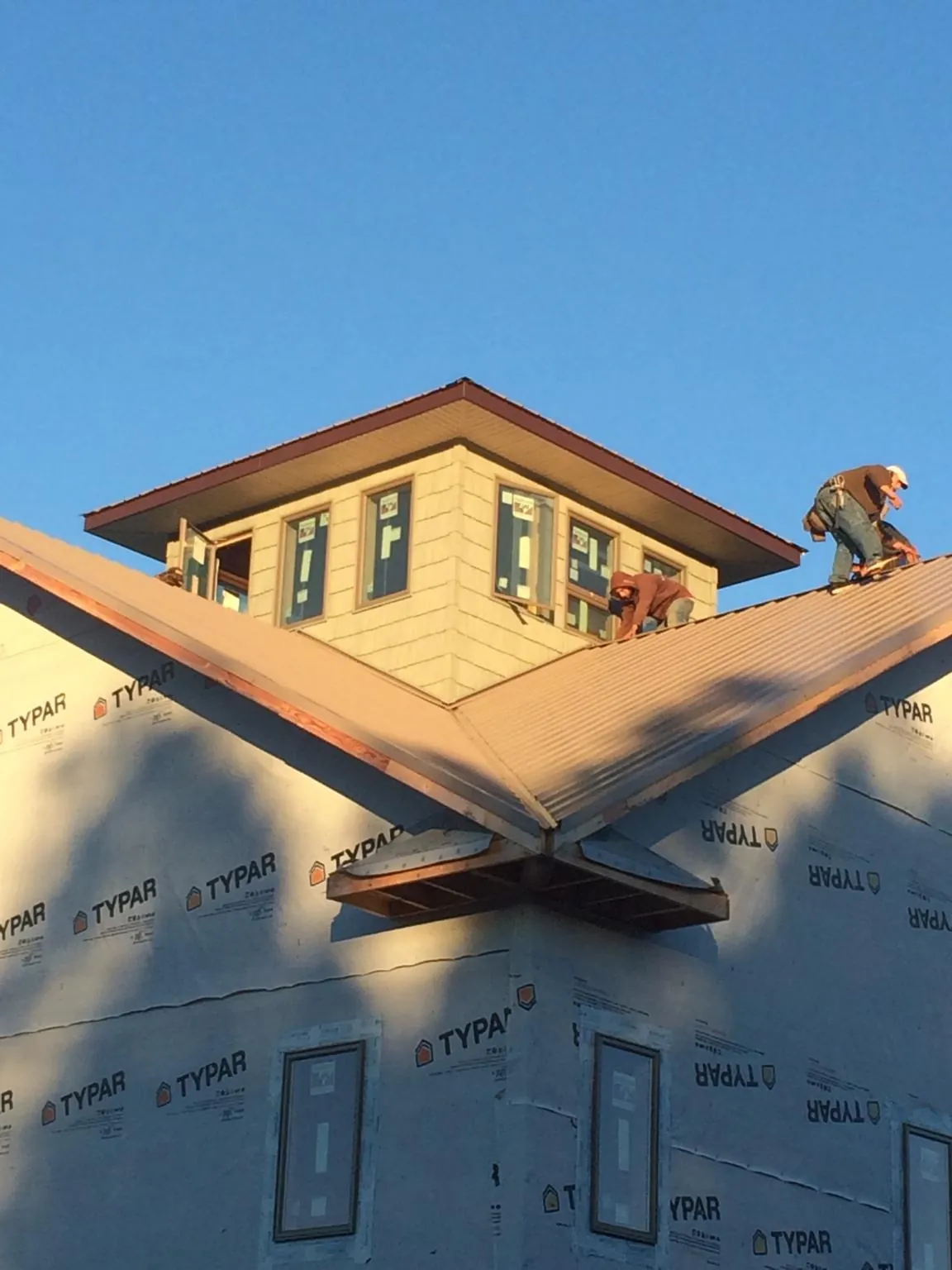 Roofers working around a rooftop cupola on a new metal roof at sunset — Roof Waterproofing in Chattaroy by Roofing Brothers